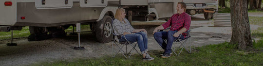 Couple sits in lawn chairs by RV with SnapPads installed to the stabilizing feet